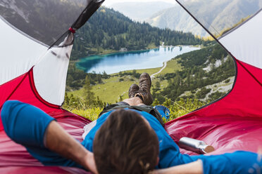 Austria, Tyrol, Hiker relaxing in his tent in the mountains at Lake Seebensee - DIGF04785