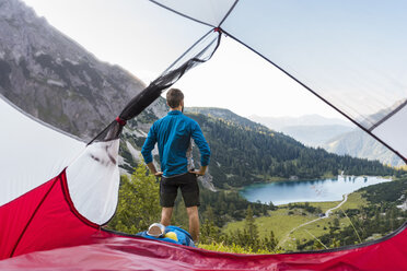 Österreich, Tirol, Wanderer steht an seinem Zelt in den Bergen und schaut auf den Seebensee - DIGF04786