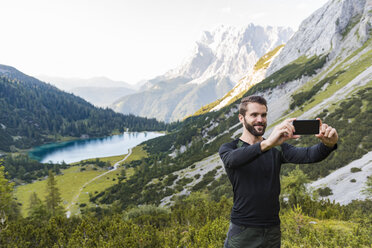 Österreich, Tirol, Wanderer macht Selfies mit seinem Smartphone am Seebensee - DIGF04789