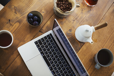 Blick von oben auf einen Laptop, eine Kaffeekanne und eine Tasse Kaffee auf einem Tisch. - MINF07707