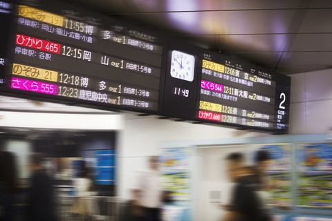 Nahaufnahme einer beleuchteten Abfahrtstafel mit Uhr in einem japanischen Bahnhof., lizenzfreies Stockfoto
