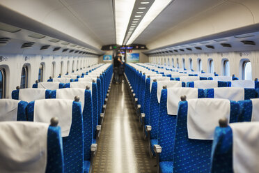 Innenansicht eines Reisezugwagens mit blauen Sitzen, Menschen im Hintergrund. - MINF07748