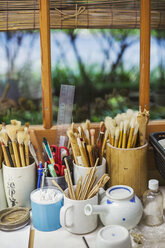 Close up of a selection of paintbrushes and tools in a Japanese porcelain workshop. - MINF07752