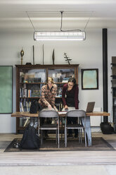 Zwei Frauen sitzen um einen Tisch im Bürobereich einer Metallwerkstatt und sehen sich einen technischen Plan an. - MINF07754