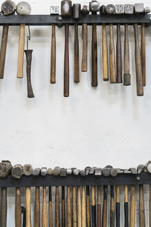 Nahaufnahme einer Auswahl von Hämmern, die an einer Wand in einer Metallwerkstatt hängen. - MINF07765
