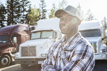 Black man truck driver near his truck parked in a parking lot at a truck stop - MINF07802