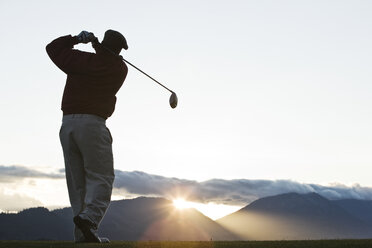 Ein Golfer, der bei Sonnenaufgang abschlägt. - MINF07839