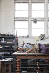 Black woman factory worker taking a nap on top of a work station in a woodworking factory. - MINF07860