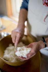 Close up of woman standing at a table in a kitchen, making sushi. - MINF07876