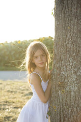 Girl standing on tree trunk at summer evening - LVF07390