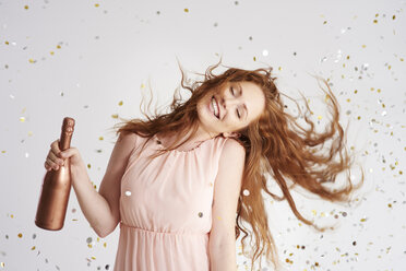 Porträt einer glücklichen jungen Frau, die mit einer Flasche Champagner tanzt - ABIF00888