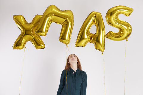 Junge Frau mit goldenen Luftballons, die das Wort 