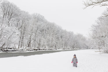 Junges Mädchen steht an einem von Bäumen gesäumten Fluss im Schnee. - MINF08005