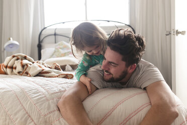 Man and smiling young girl lying on a bed. - MINF08012