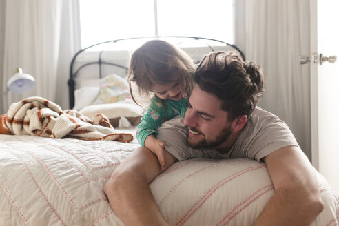 Ein Mann und ein lächelndes junges Mädchen liegen auf einem Bett. - MINF08012