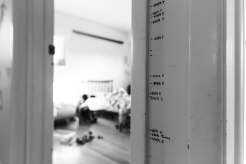 Close up of handwritten height marks on a door frame, door ajar. - MINF08013