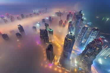 Luftaufnahme einer Stadtlandschaft mit beleuchteten Wolkenkratzern über den Wolken in Dubai, Vereinigte Arabische Emirate, in der Abenddämmerung. - MINF08041