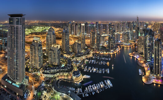 Aerial view of the cityscape of Dubai, United Arab Emirates at dusk, with illuminated skyscrapers and the marina in the foreground. - MINF08051