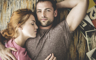 A couple lying together on a rug next to a pile of records. - MINF08076