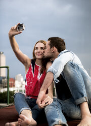 Ein Paar posiert für ein Selfie auf dem Dach einer Stadt. - MINF08106