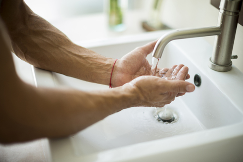 Nahaufnahme einer Person, die sich die Hände an einem Waschbecken wäscht., lizenzfreies Stockfoto