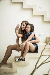 A woman and a girl sitting on outdoor steps posing for a selfie. - MINF08133