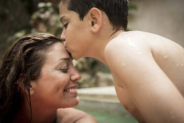 A boy kissing the forehead of a woman in a swimming pool. - MINF08141