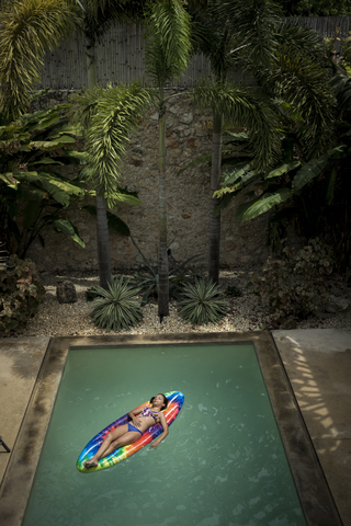 A girl with eyes closed lying on a pool raft in a swimming pool. stock photo