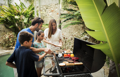A family standing at a barbecue cooking food. - MINF08157