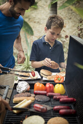 A man and boy standing at a barbecue cooking food. - MINF08160