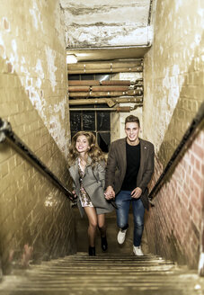 A young couple running up a flight of stairs. - MINF08188