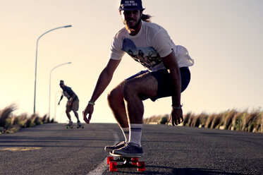 Ein junger Mann fährt mit dem Skateboard auf einer Straße. - MINF08192