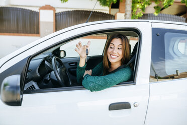 Woman in the interior of a car, looking happy at the keys - KIJF01991