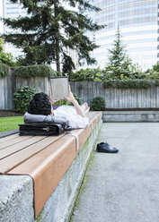 Businessman in a downtown city park taking a break and checking his computer notebook - MINF08209