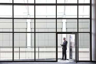 Businessman on a small office balcony checking his phone. - MINF08216