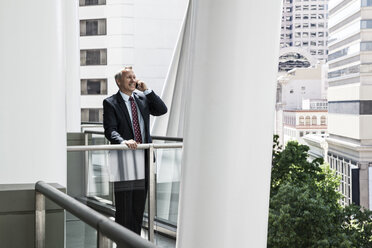 Caucasian businessman on the phone while standing on an office balcony. - MINF08232