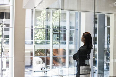 Businesswoman standing in a conference room window in a large business centre. - MINF08240