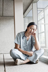 Asian woman doctor in scrubs in a hospital hallway. - MINF08275