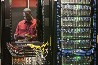 Black man technician working on computer servers in server farm. - MINF08283