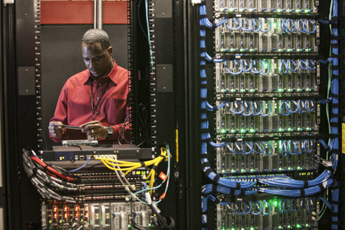 Schwarzer Techniker bei der Arbeit an Computerservern in einer Serverfarm. - MINF08283