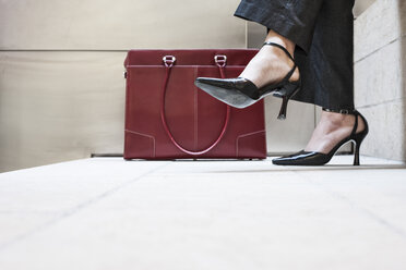 Businesswoman's feet in high heeled shoes and her purse. - MINF08287