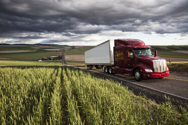 Ein Lastwagen fährt bei Sonnenuntergang durch die Weizenfelder im östlichen Washington, USA. - MINF08330