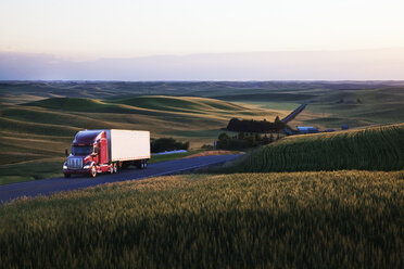 Commercial truck driving though wheat fields of eastern Washington, USA at sunset. - MINF08331