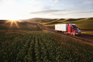 Peterbilt Class8 commercial truck driving through farmlands in eastern Washington, USA at sunset. - MINF08333