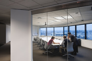 View from outside a conference room looking in at a team of people working late in the day. - MINF08347