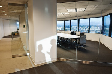 Shadows of two business people on the wall outside of a company conference room.. - MINF08348