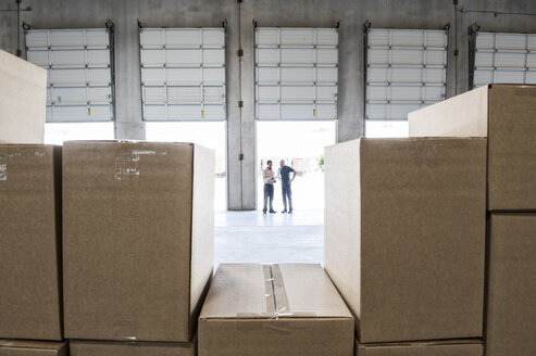 Team of workers check out inventory in front of loading dock doors in a new warehouse. - MINF08357