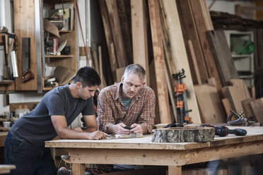 Ein Team von zwei kaukasischen Fabrikarbeitern löst ein Problem an einem Arbeitsplatz in einer Holzverarbeitungsfabrik. - MINF08376