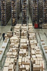 Interior view of a large distribution warehouse with products in cardboard boxes stacked on pallets and large storage racks. - MINF08401