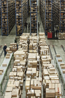 Innenansicht eines großen Auslieferungslagers mit Produkten in Kartons, die auf Paletten gestapelt sind, und großen Lagerregalen. - MINF08401